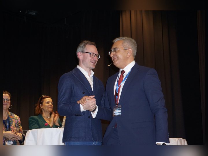 Prof. Georgi Chaltikyan is greeting a colleague on the conference stage