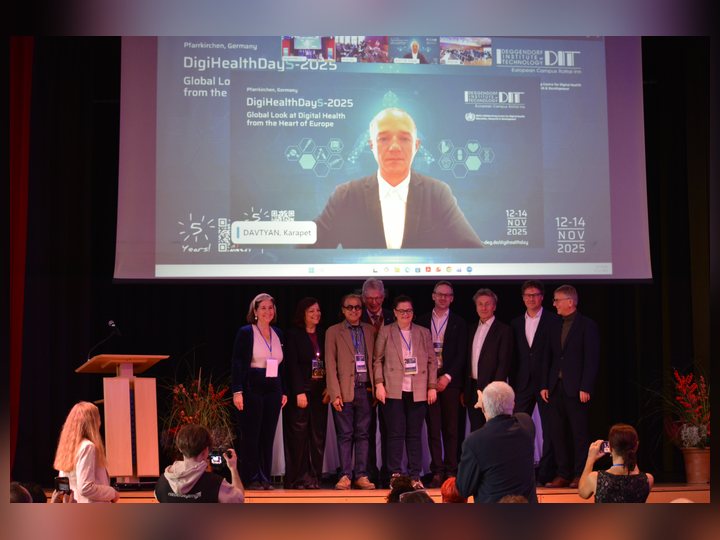 The same remote colleague joining speakers and organisers for a stage photograph